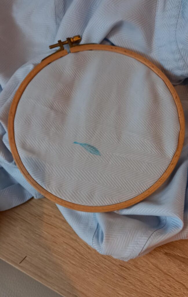 Réparation textile d'une chemise par la broderie : Dessin au marqueur d'une plume recouvrir la tache. Tissu tendu dans le tambour.